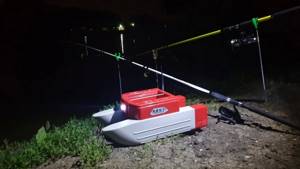 Photo of a feeding boat at night with fishing rods and lights on