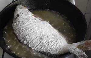 whole carp fried in a frying pan