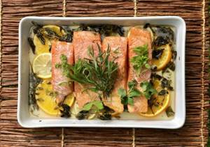 Baked coho salmon with vegetables and lemon wedges