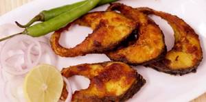 fried carp steaks on a plate with onions, peppers and lemon